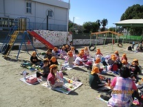 園庭でお弁当給食を楽しむ5歳児の写真