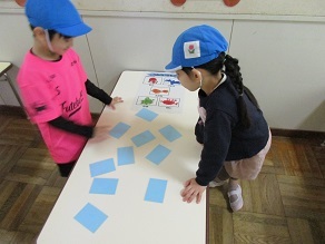 幼稚園のごっこ遊びで友達と一緒に絵合わせカードをして遊んでいる様子の写真