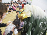 獅子が子どもの頭を噛んで祈願している様子の写真