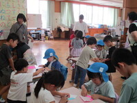 写真:小学生に折り紙を教えてもらっているところ