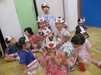 お面をかぶって笑顔の2歳児の様子の写真