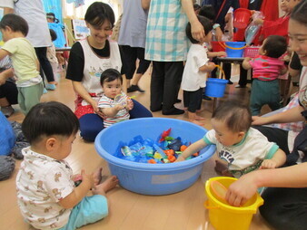 0歳児が魚すくいコーナーで遊んでいる様子の写真