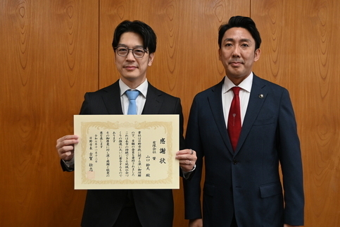 感謝状贈呈式にて、賞状を持つ株式会社賛代表ヤマグチミキオ様と日野市長