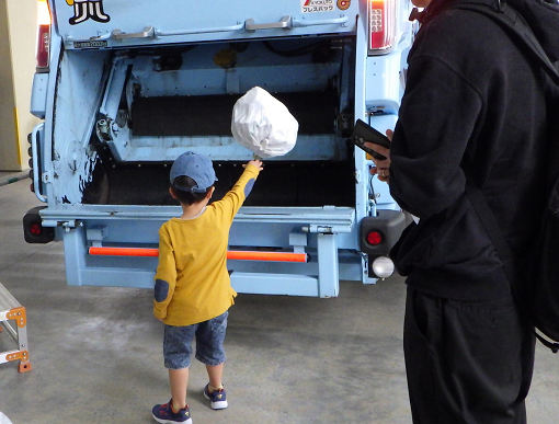 参加者がごみ収集車にごみを投げ入れている写真