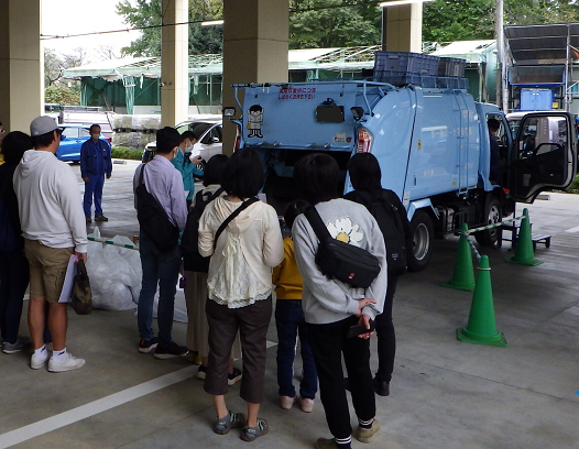 ごみ収集車の後ろに人が集まっている写真