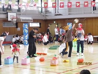 1歳児クラスの子どもたちが赤ずきんちゃんに変身し、お父さんお母さんと手をつないで歩いている様子