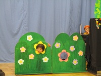 0歳児が草の装飾から顔を出して隠れている様子の写真