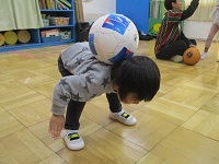 ボールを背中に乗せて遊ぶ子供の様子の写真