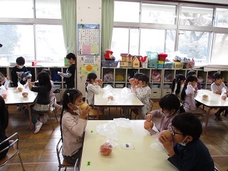 5歳児の子ども達が保育室でりんごの手に持っている様子の写真