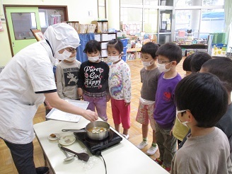 栄養士による芋汁づくりのデモンストレーションを5歳児クラスの子ども達が見ている様子の写真