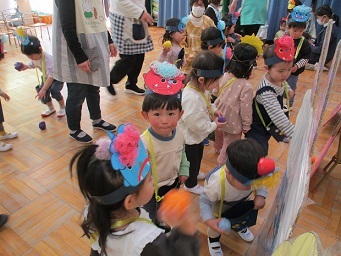 1歳児りす組が鬼ボードに向かって手作り豆を投げている様子。