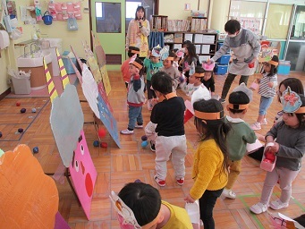 2歳児うさぎ組が鬼ボードに向かって手作り豆を投げている様子。