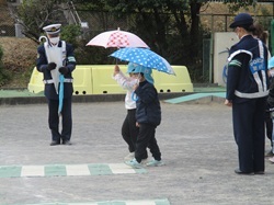 傘をさして横断歩道を渡る練習をする5歳児の写真