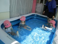写真:2歳児がプールに入って気持ちよさそうに座っている様子